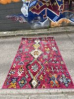 Front view of the tribal design rug showing vibrant multicolored geometric patterns on a magenta background.