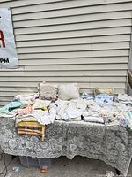 Wide view of vintage linens and embroidered pieces displayed on a table, showing various folded textiles and pillow covers with lace and embroidery.