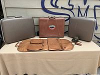 Group photo of two gray hard suitcases, one brown leather suitcase with Canada Pacific sticker, tan leather roll-up organizer, and small coin pouch arranged on a table.