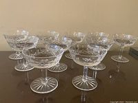 Ten crystal coupe glasses arranged in rows on a tabletop