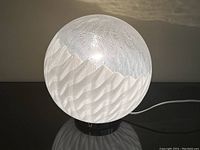 Front view of lamp lit showing opaque wave pattern on lower half of globe and bubbled texture above