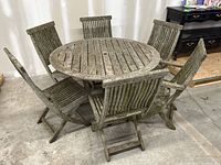 Full front view of round teak table surrounded by six chairs