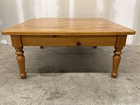 Front view showing the pine coffee table with turned legs and square top surface.