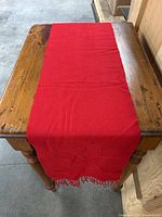 Full view of red cashmere scarf laid flat on wooden table, showing length and color.