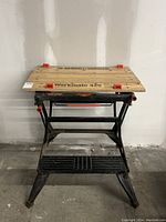 Front view of Black & Decker Workmate 425 portable workbench showing wooden top, metal frame, and orange adjustment knobs.