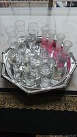 Top view showing all 15 shot glasses arranged on a silver serving tray on a clear glass table.
