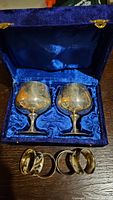 Two silver plated brandy snifters in blue satin-lined case with four silver plated napkin rings below
