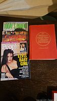 Photo showing all four items: three magazines including People Weekly, Canadian Living, Today's Parent, and a red hardcover Webster's Dictionary.