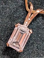 Close-up front view of emerald cut fancy color lab-created diamond pendant set in 10K gold.