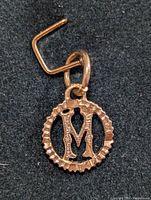 Close-up image of 10K gold pendant with letter M showing design details.