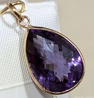Close-up image of the pear-shaped purple amethyst stone set in yellow gold pendant viewed from the front.