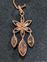 Front close-up view of 14K rose gold floral pendant with three marquise-cut natural diamonds hanging from petals.