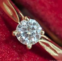 Close-up front view of the ring's round brilliant lab diamond held by four prongs on the 10K gold band.