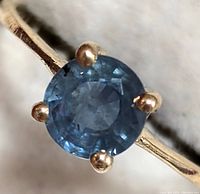 Close-up top view of round faceted blue sapphire and four-prong setting