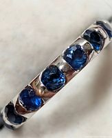 Close-up of ring section showing three round blue sapphires set in white gold