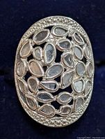 Close-up photo of the silver-tone stainless steel oval ring showing multiple pear-shaped natural diamonds in a cluster pattern with textured border.