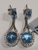 Close-up image showing front view of the sterling silver earrings with blue topaz center stones and CZ halo.