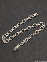 Clear image of the sterling silver chain bracelet laid flat on a black surface, showing the overall length and links.