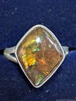 Close-up front view of kite-shaped Ammolite stone set in silver bezel, showing colorful iridescent hues and smooth surface.