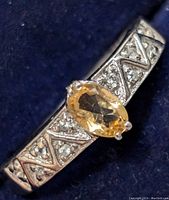 Close-up of the silver ring featuring an oval citrine stone in the center with detailed design work on the band.