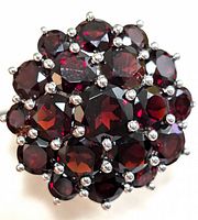 Close-up top view showing multiple faceted round garnet stones set in a cluster style with silver prongs.