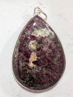 Close-up front view of the teardrop-shaped pendant highlighting the purple and white gemstone set in silver.