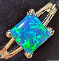 Top angled close-up of the square opalite stone set in a silver ring band showing blue and green colors.