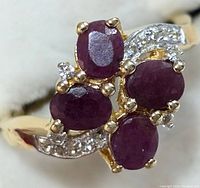 Close up of the ring's front showing four oval ruby stones and small white topaz accents.