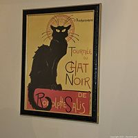 Photo of a framed vintage poster 'Tournée du Chat Noir de Rodolphe Salis' featuring a black cat on yellow and red background.