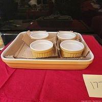 Front angled view of the rectangular casserole dish containing four yellow and white ramekins secured with cardboard separators.