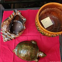 Overview of all three ceramic items including the shell bowl, turtle figurine, and planter on a red cloth