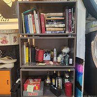 Three shelving cubes stacked vertically; filled with books, miscellaneous items, and bottles for demonstration only, contents not included in lot.