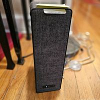 Front view of the black IKEA Symfonisk Sonos Wi-Fi bookshelf speaker with fabric grille and power indicator light.