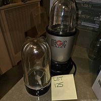 Magic Bullet blender base with one extractor cup attached showing the blade inside. Lot number written on sticky note.