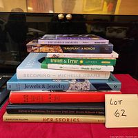 Photo of a stack of nine books with a note labeled Lot 62 showing titles and authors.
