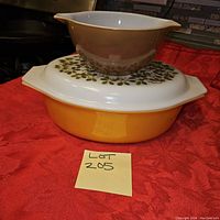 Stacked view of three Pyrex bowls showing orange bowl with lid at bottom, white bowl with green floral pattern in middle, and plain white bowl on top.
