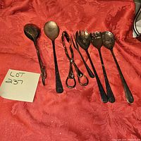 Full view of all six pieces in the silver serving set arranged on a red cloth background showing general condition and tarnish.