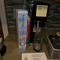 Photo of SodaStream machine with carbonating bottle attached, SodaSodgy syrup box, and carbonator cylinder