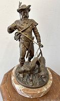 Front view of bronze huntsman sculpture with two dogs on oval marble base