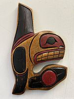 Front view of the whale wood wall carving showing the carved and painted details in red, black, and natural wood color.