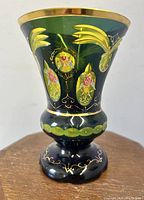 Front view of faceted green vase with yellow enamel medallions and gilt rim