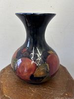 Front angled view of the dark blue ceramic vase decorated with hand-painted pomegranate fruit motif.