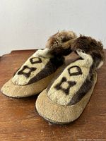 Front and side view of traditional mukluks showing fur pattern, leather soles and fur trim on opening.