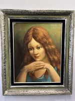 Full front view of the framed oil painting showing the young woman with auburn hair and resting chin pose.