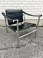 Front view of chair showing black leather sling seat and chrome tubular frame.