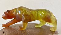 Left side full view of amber glass panther on wooden surface