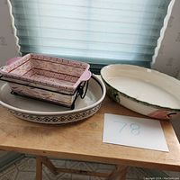 Four ceramic casserole bowls placed together on a wooden table beside a window.