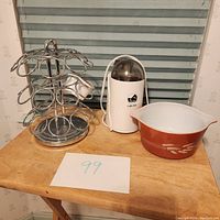 Coffee stand holding area, La Pavoni coffee mill grinder, and Pyrex wheat patterned bowl on wooden table.