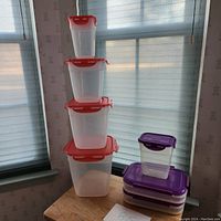 Stacks of plastic containers; left stack is nested set of 4 containers with red lids, right stack includes 3 flat containers and 1 small container with purple lids