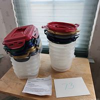 Stack of 5 round and 5 rectangular translucent plastic food storage containers with assorted colored locking lids, set displayed on wooden surface with care sheet and lot number visible.
